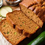 Moist slice of banana zucchini bread on a wooden board.