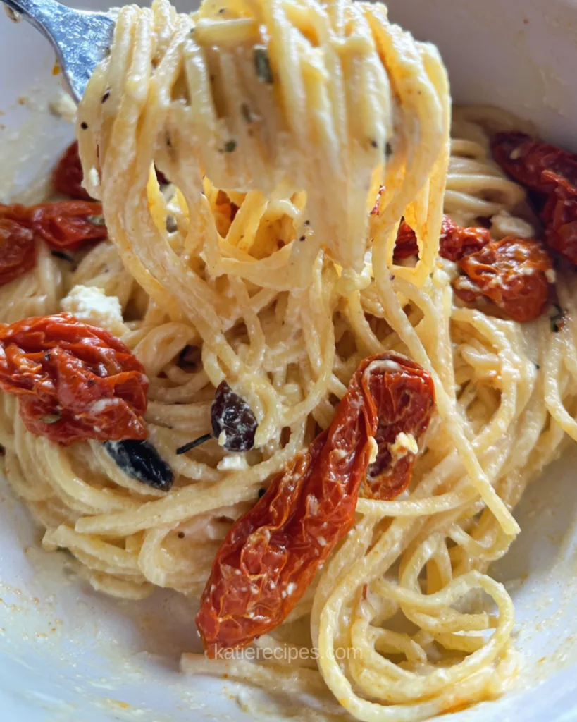 Creamy feta pasta sauce coating spaghetti with Kalamata olives and roasted tomatoes