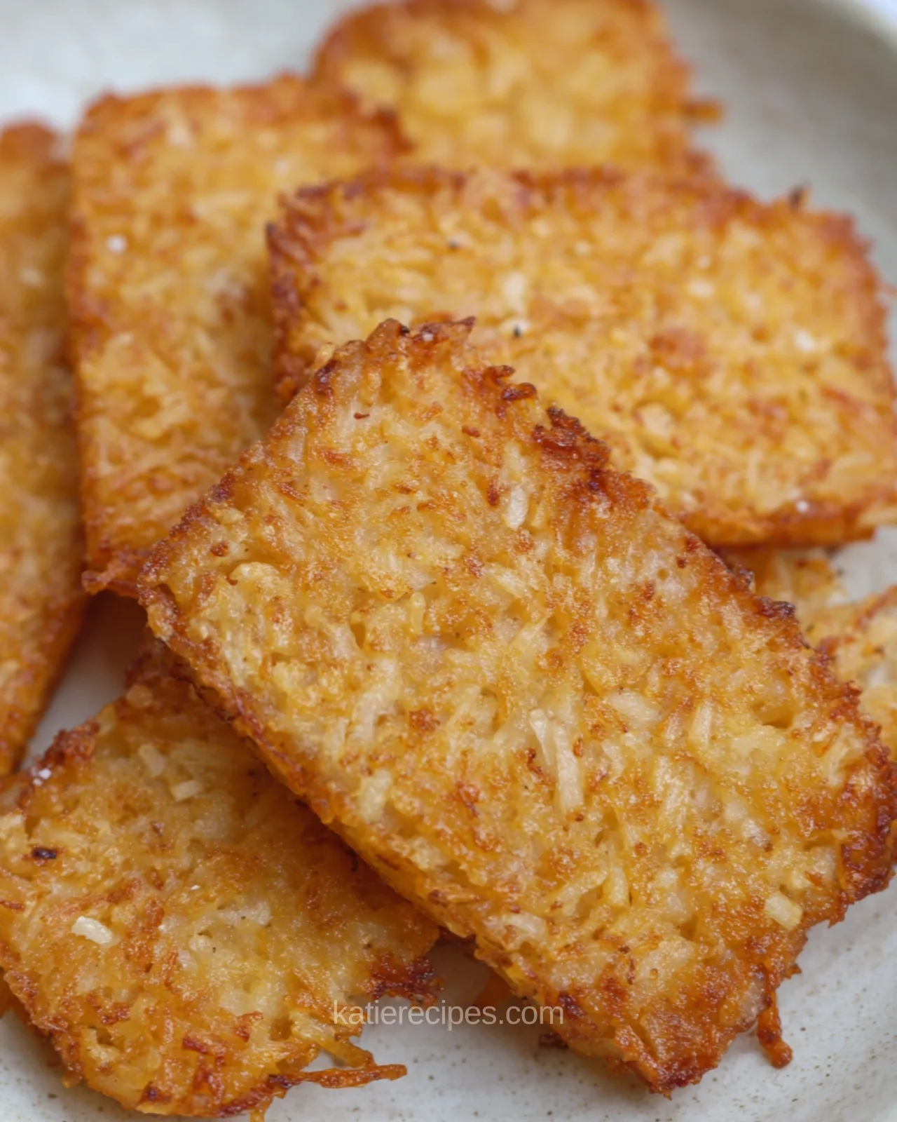 Golden crispy hash brown patties cooked in the air fryer on a ceramic plate