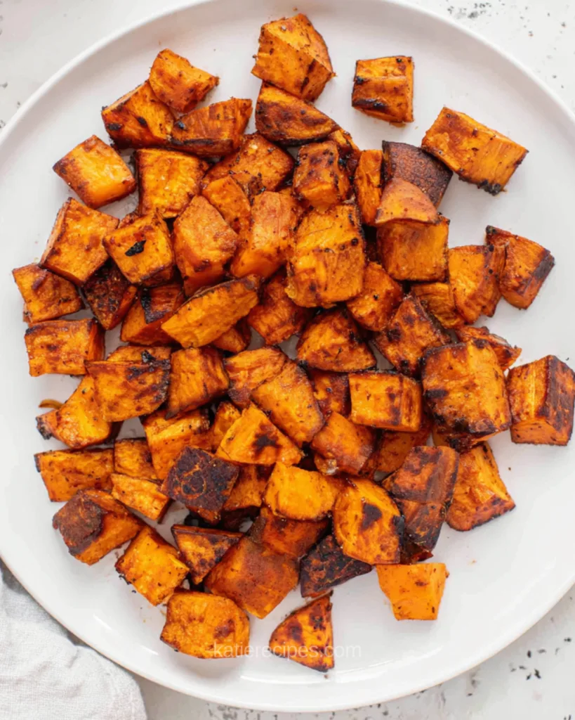 Overhead view of caramelized air fryer sweet potato cubes on a white plate