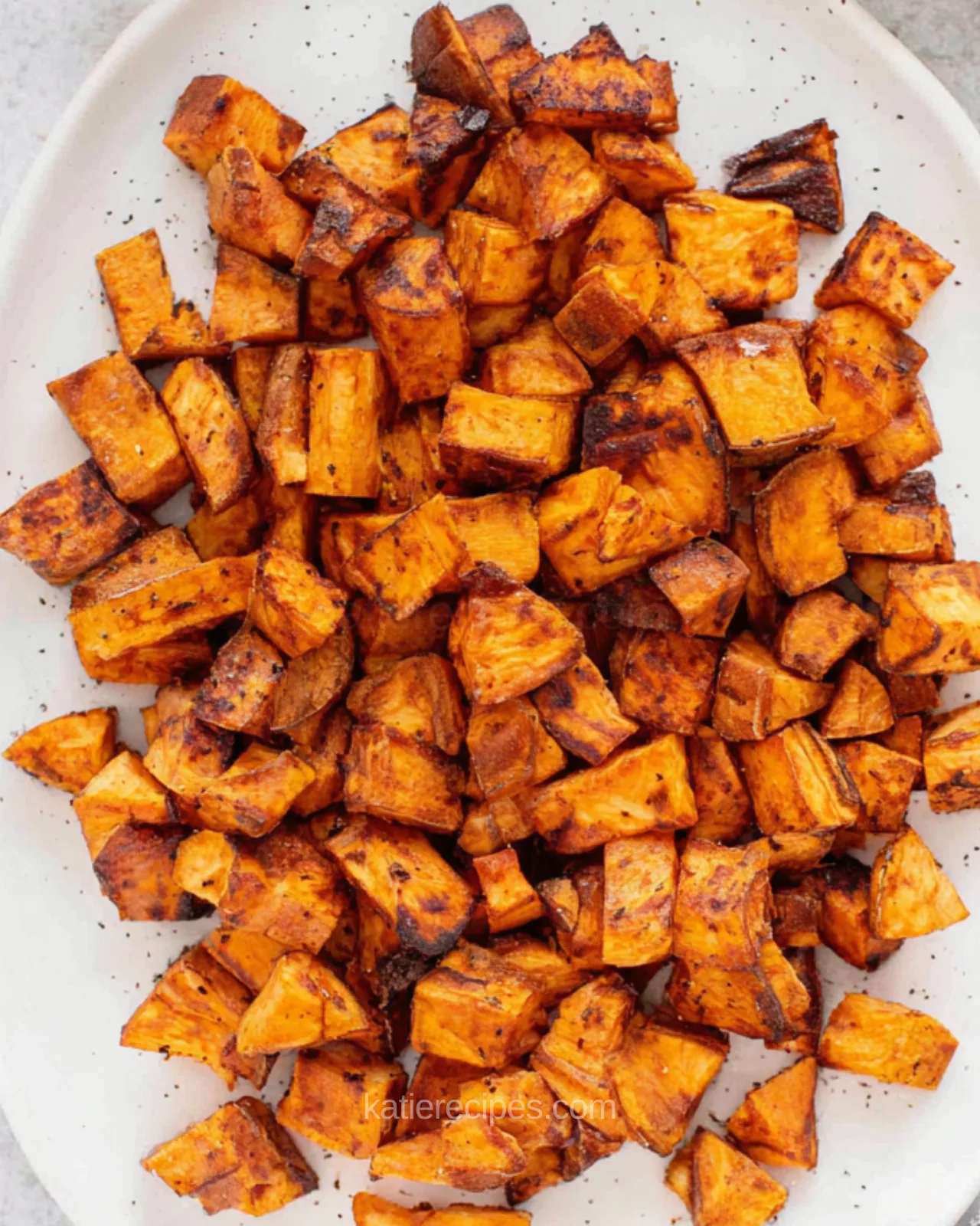 Air fryer sweet potato cubes served on a white oval platter with black pepper