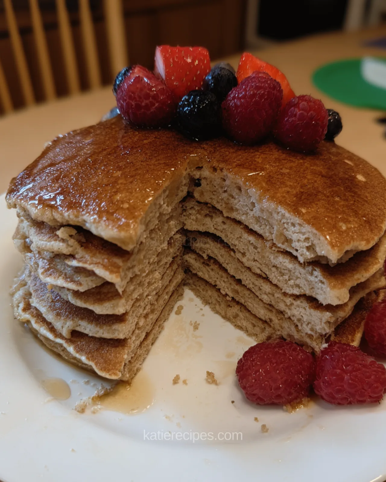 Stack of fluffy Kodiak pancakes with a slice cut out, topped with fresh berries