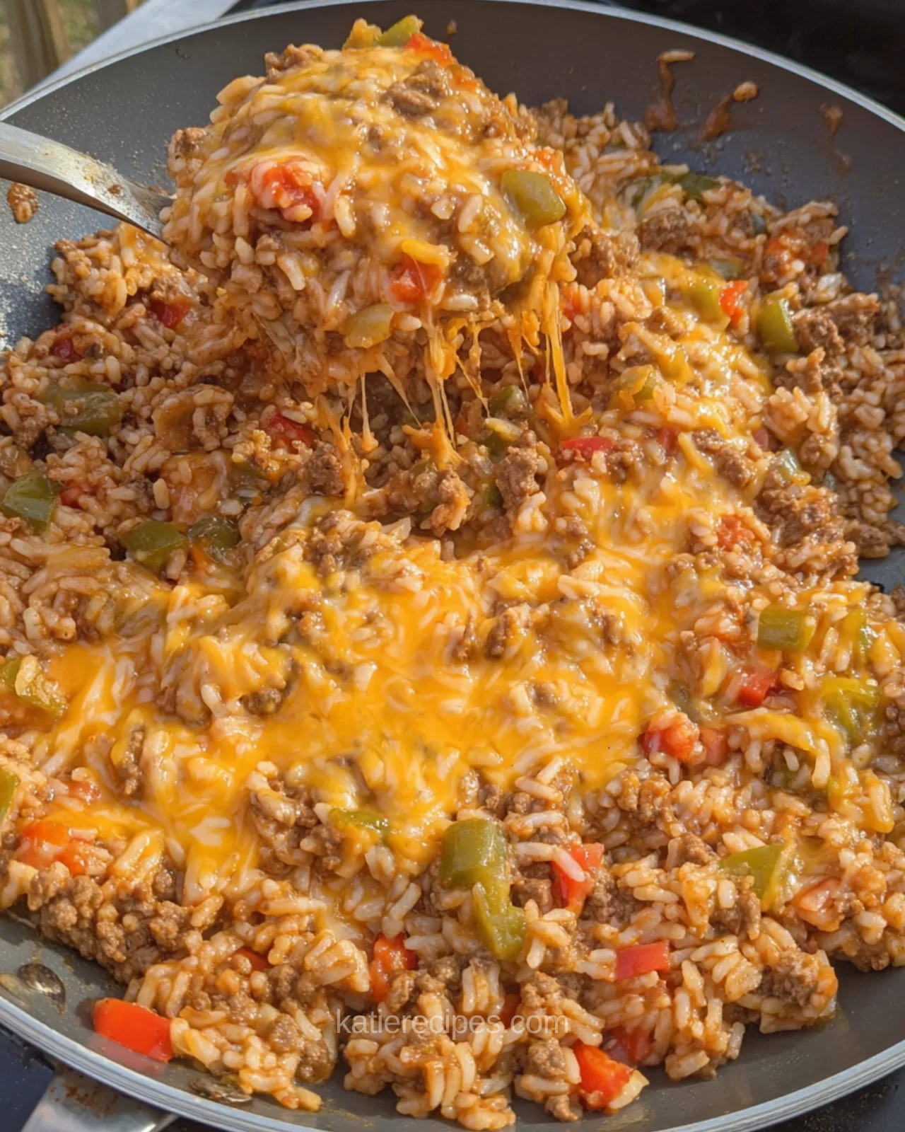 Spoonful of cheesy unstuffed pepper skillet with melted cheddar stretching from the pan