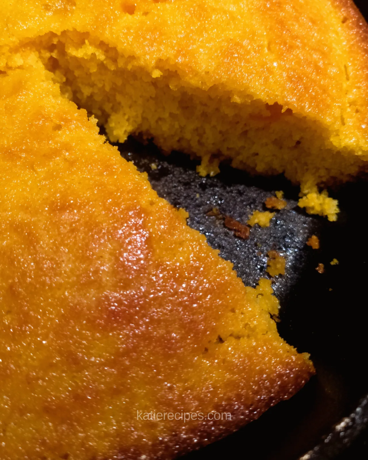 Honey butter glaze soaking into warm sweet potato cornbread in a cast iron skillet