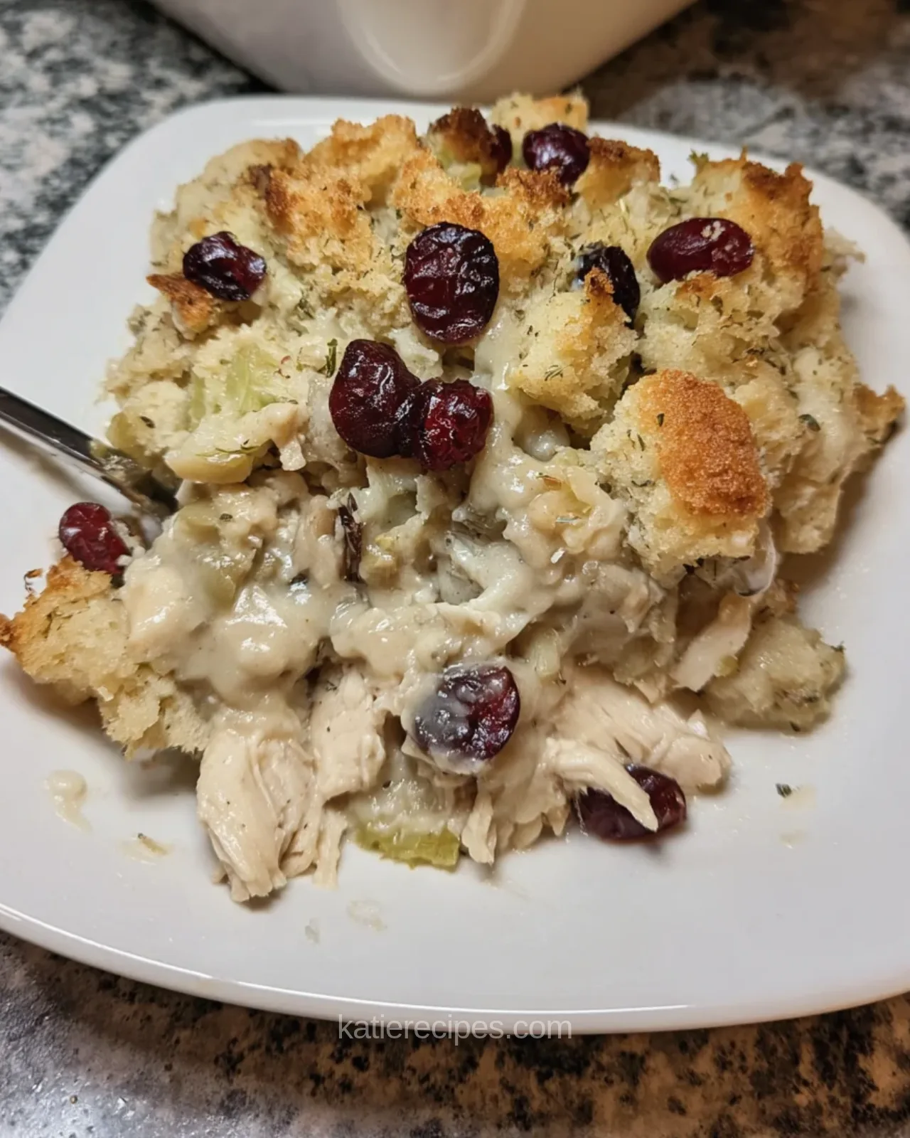 Serving of chicken and stuffing casserole with golden stuffing topping, creamy chicken and cranberries on a white plate
