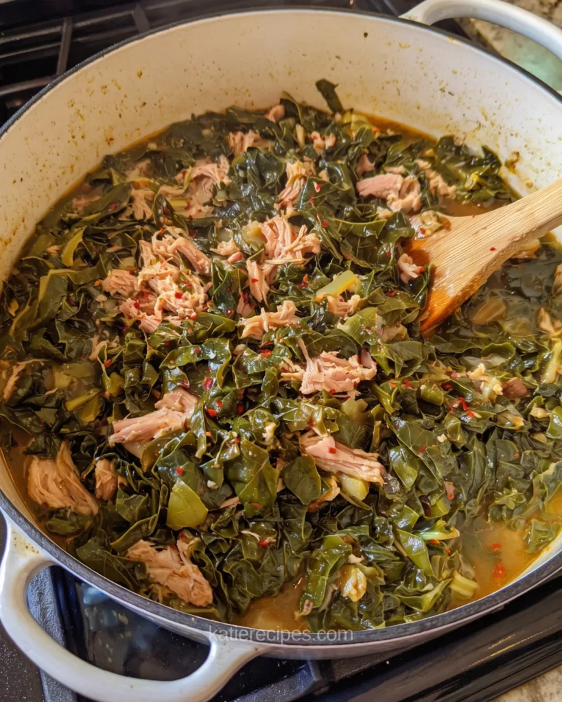 Large white pot of Southern collard greens with shredded smoked turkey and red pepper flakes simmering on the stove